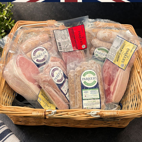 A wicker basket filled with packaged cured meats from Parker's, including British back bacon, and sausages.